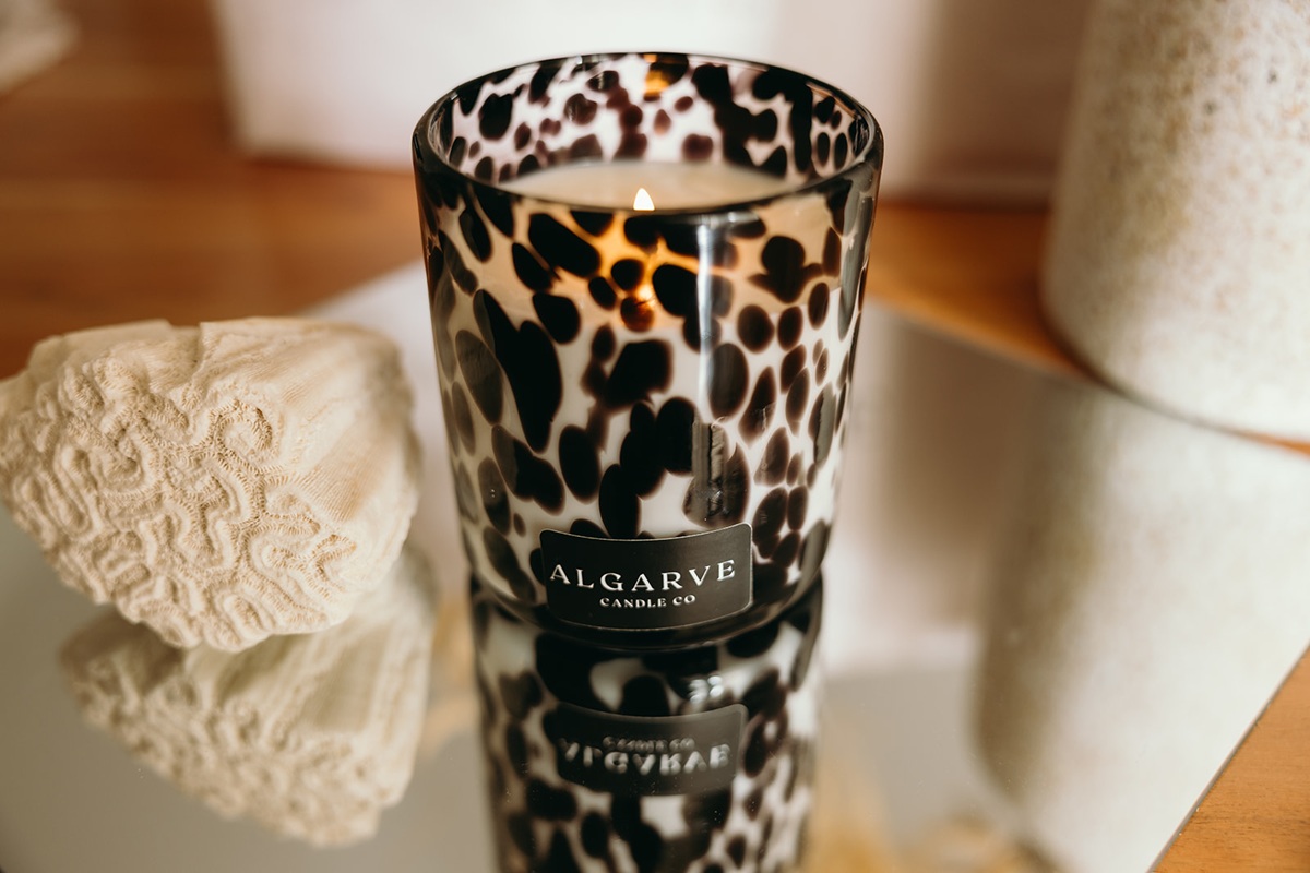 Lit Algarve Candle Company soy candle in patterned glass on a mirrored surface