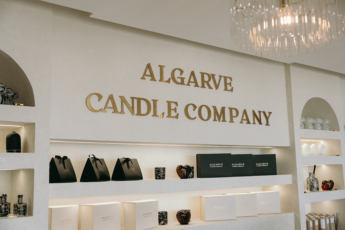 Algarve Candle Company retail wall with gold lettering and illuminated product shelves, Quarteira