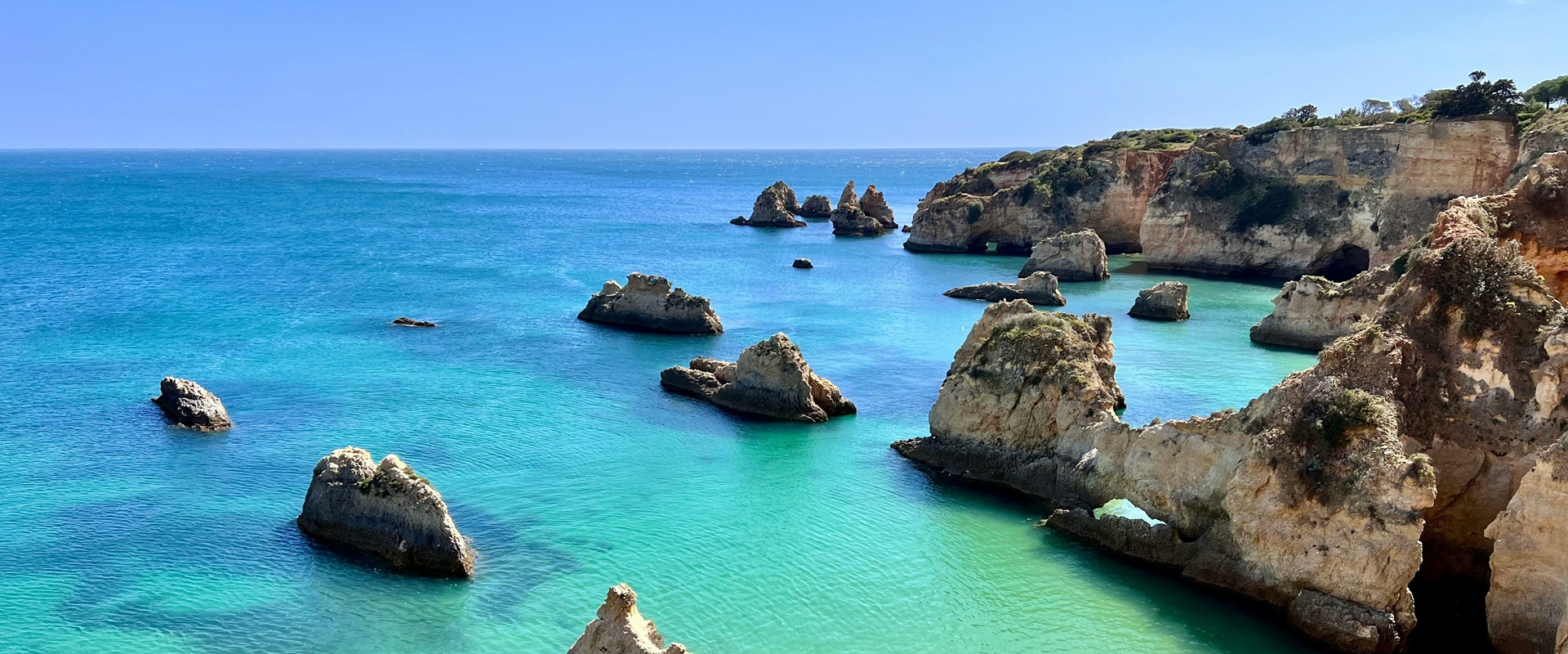 Turquoise Atlantic water and golden limestone cliffs on the Algarve coast, Portugal