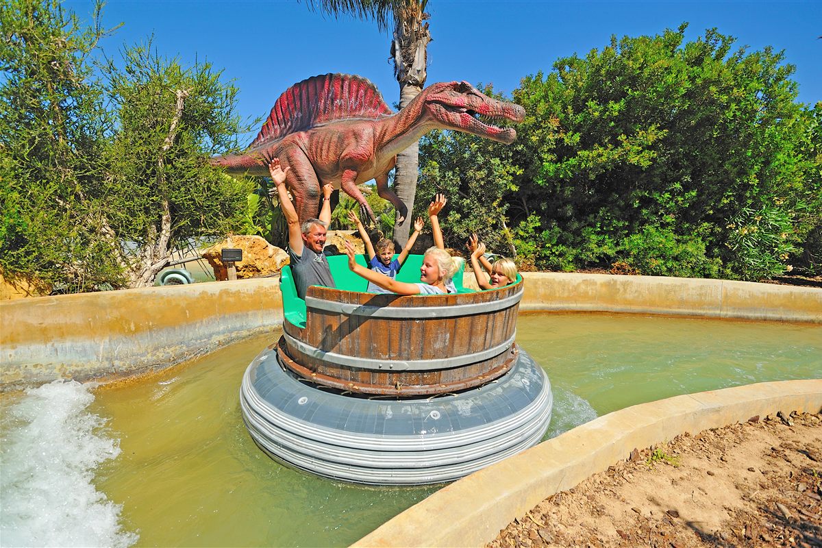 Family on a water rapids ride beside a Spinosaurus model at Zoomarine